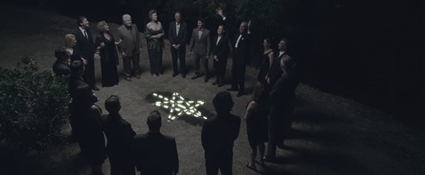 Gathered around the ritualistic pentagram, these old rich "respectable" people keep repeating "Hail Astraeus". Sarah appears to be buried underneath the pentagram.