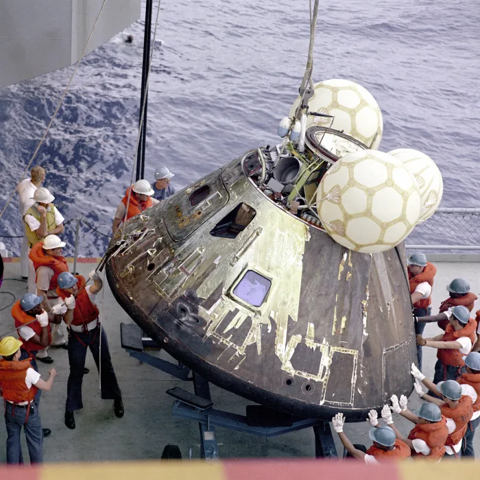 Crew members of USS Iwo Jima, the main rescue ship for the Apollo 13 mission, lift the command module aboard.  NASA